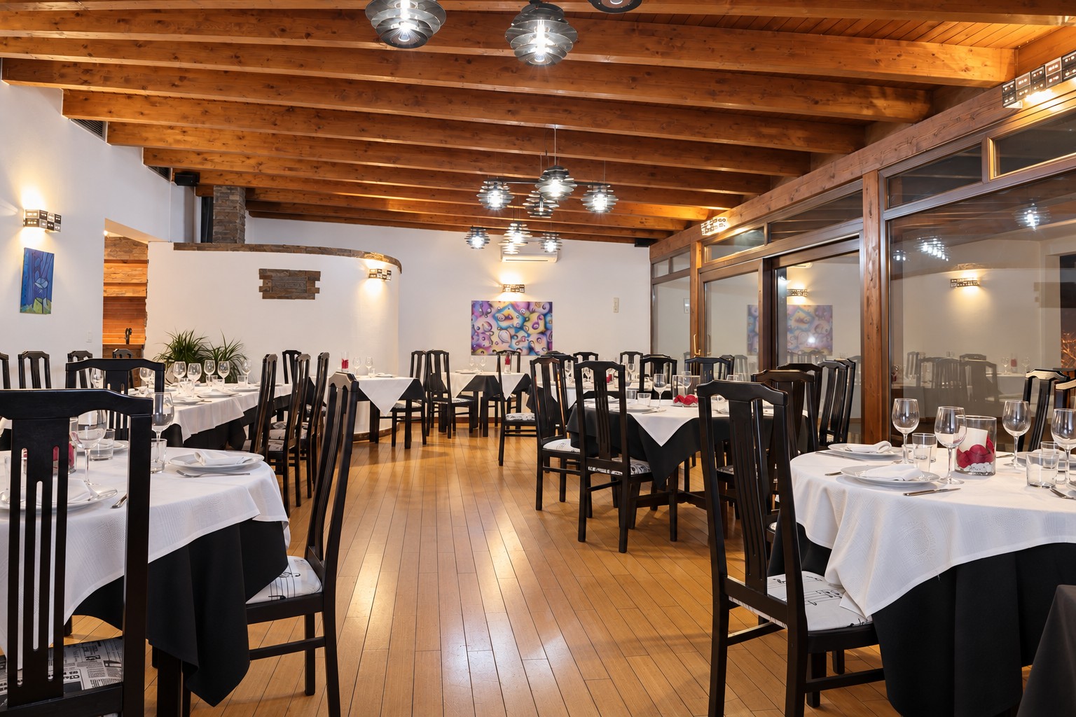 Comedor de KANDRAK con vigas de madera y mesas vestidas